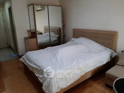 Cozy bedroom with mirrored wardrobe and wooden flooring in modern apartment.