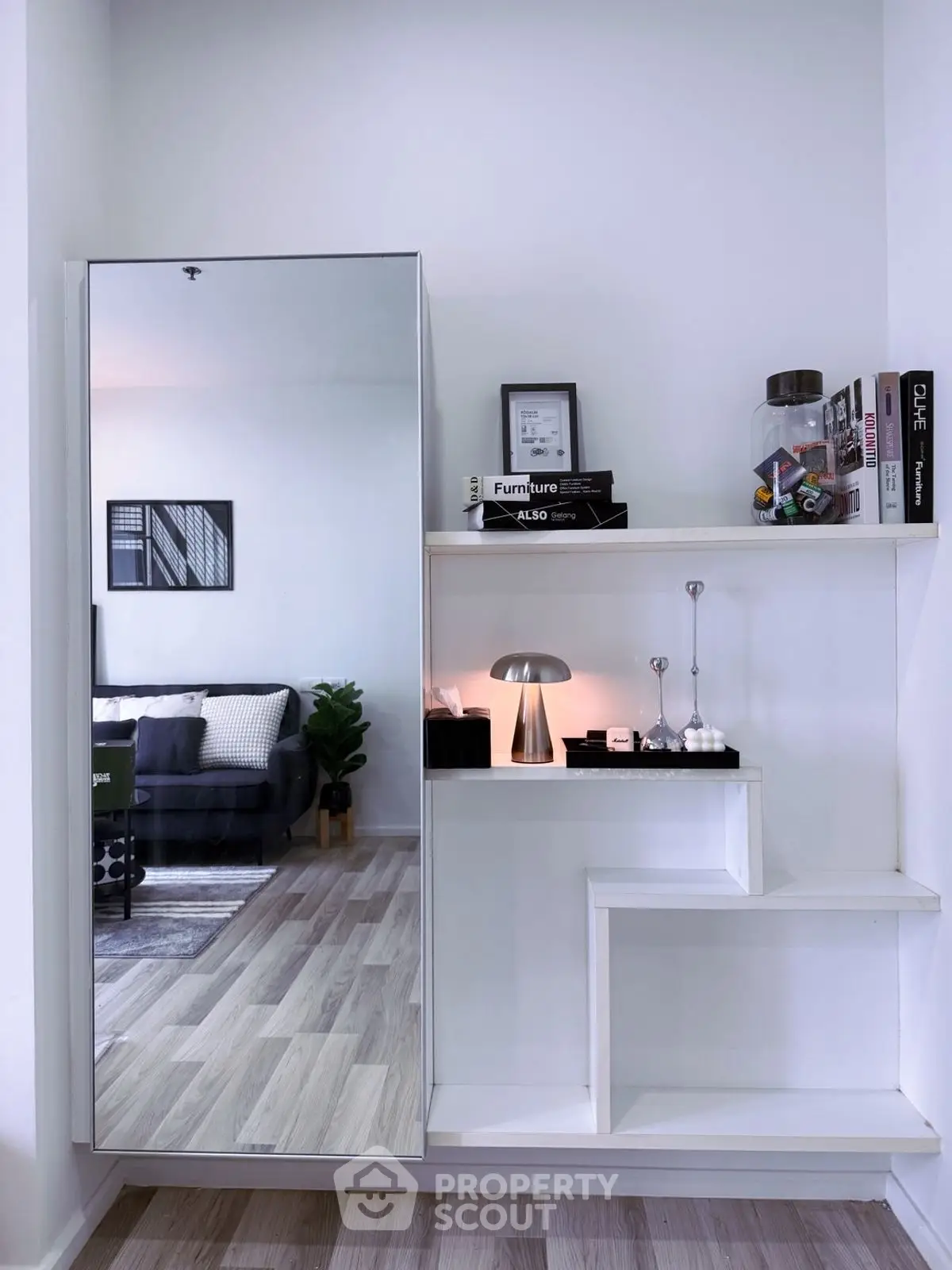 Modern living room with stylish shelving and mirror reflecting cozy sofa area.