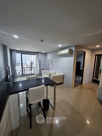 Modern living room with sleek furniture and large window offering city views.