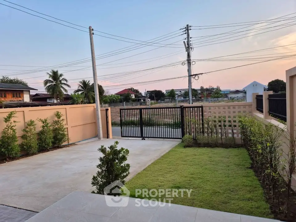 Spacious driveway with lush greenery and secure gated entrance in a serene neighborhood.