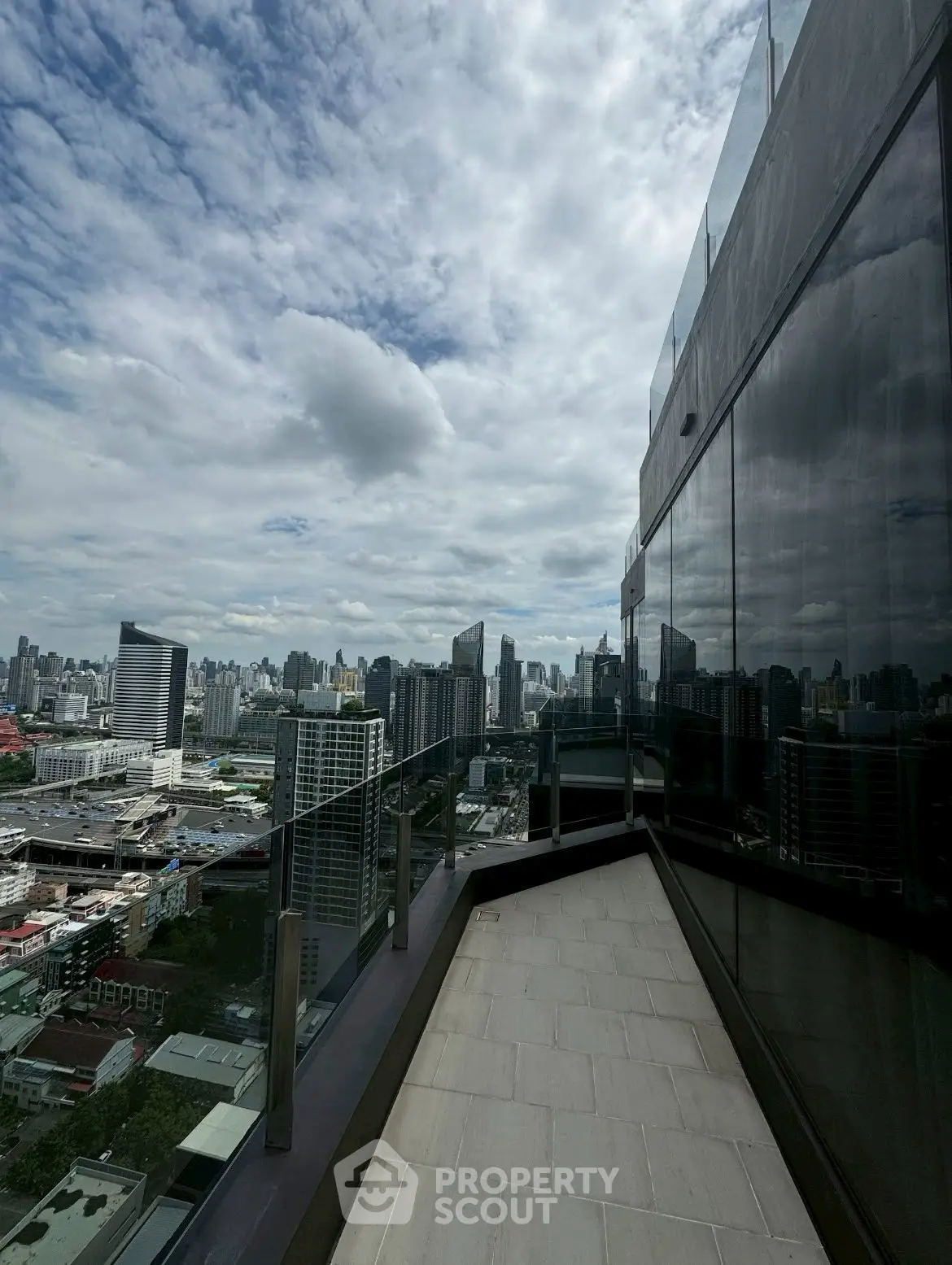 Stunning cityscape view from a high-rise balcony with glass railing and modern architecture.