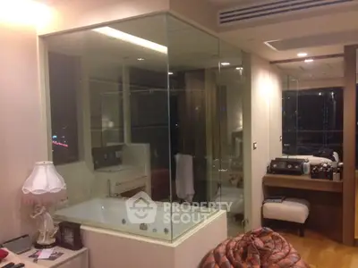 Luxurious bedroom with glass-enclosed bathtub and modern decor, perfect for relaxation and comfort.