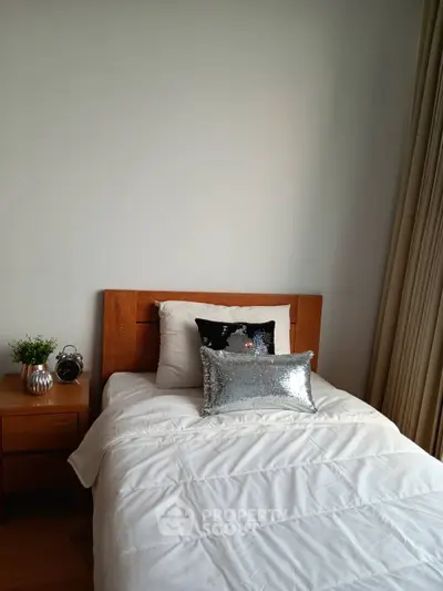 Cozy bedroom with wooden bed frame and elegant decor, perfect for relaxation.