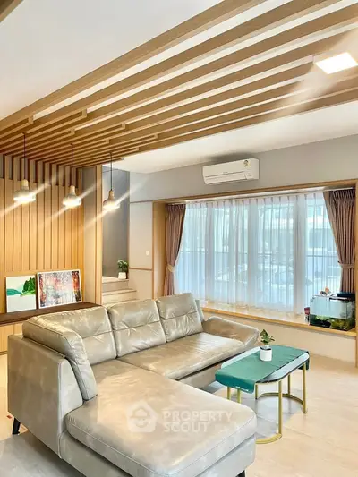 Modern living room with stylish ceiling design, cozy sectional sofa, and large windows for natural light.
