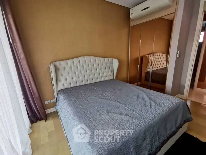 Cozy bedroom with elegant bed and mirrored wardrobe in modern apartment.