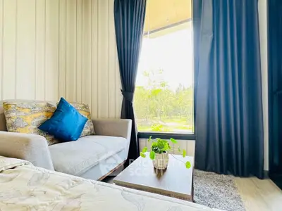 Cozy living room with stylish sofa and large window offering serene garden view.