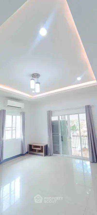 Spacious living room with modern lighting and balcony access in a bright apartment.