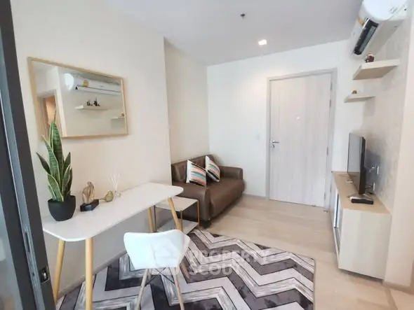 Modern living room with stylish decor and natural light, featuring a cozy sofa and sleek TV unit.
