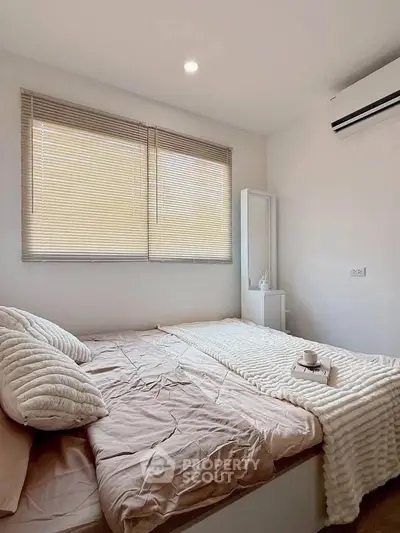 Cozy bedroom with soft lighting and modern decor, featuring a comfortable bed and air conditioning.