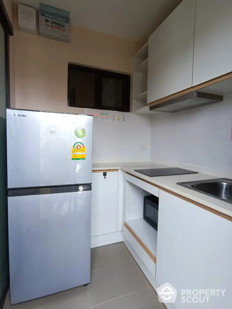 Modern compact kitchen with sleek white cabinets and stainless steel appliances