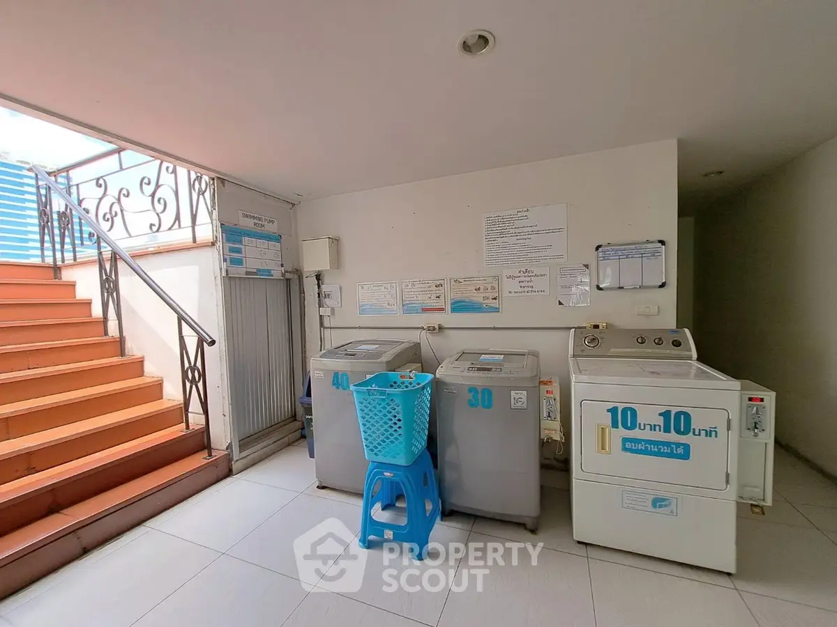 Laundry area with washing machines and staircase in a residential building