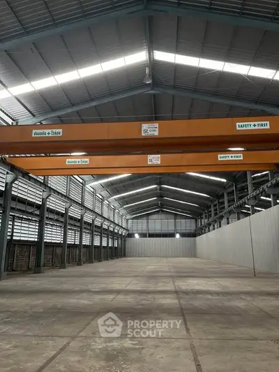 Spacious industrial warehouse with high ceilings and overhead cranes, ideal for large-scale operations.