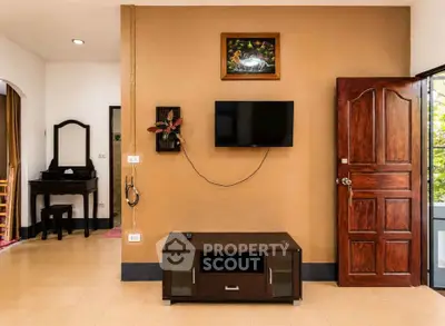 Charming living room with wall-mounted TV and elegant wooden door, perfect for cozy family gatherings.