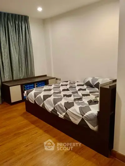 Cozy bedroom with modern decor and wooden flooring, featuring a stylish bed and elegant curtains.