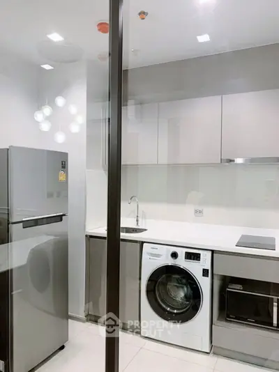 Modern kitchen with sleek appliances and washing machine in a compact layout