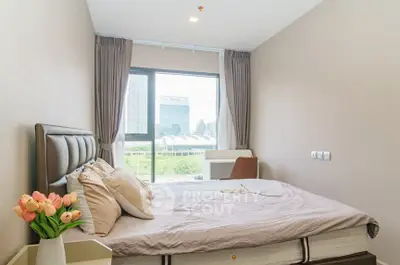 Modern bedroom with large window and city view, featuring elegant decor and cozy ambiance.