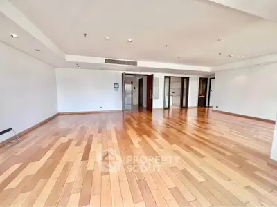 Spacious empty living room with wooden flooring and modern lighting, perfect for customization.