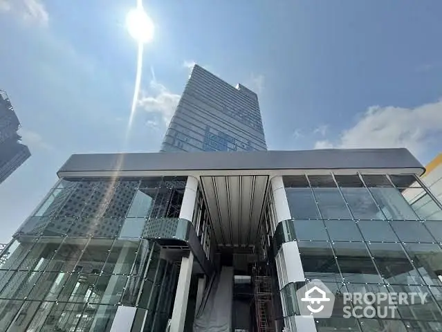 Modern glass building exterior with sleek architectural design under a clear blue sky.