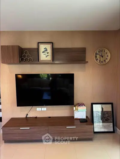 Modern living room with wall-mounted TV and stylish wooden shelves.