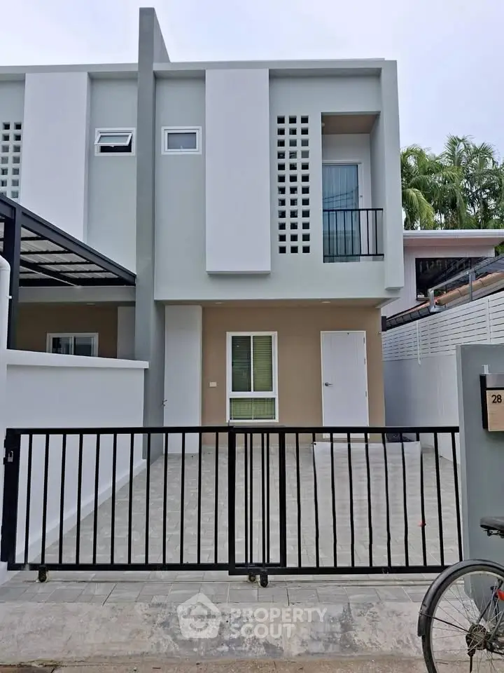 Modern two-story townhouse with gated driveway and minimalist facade.