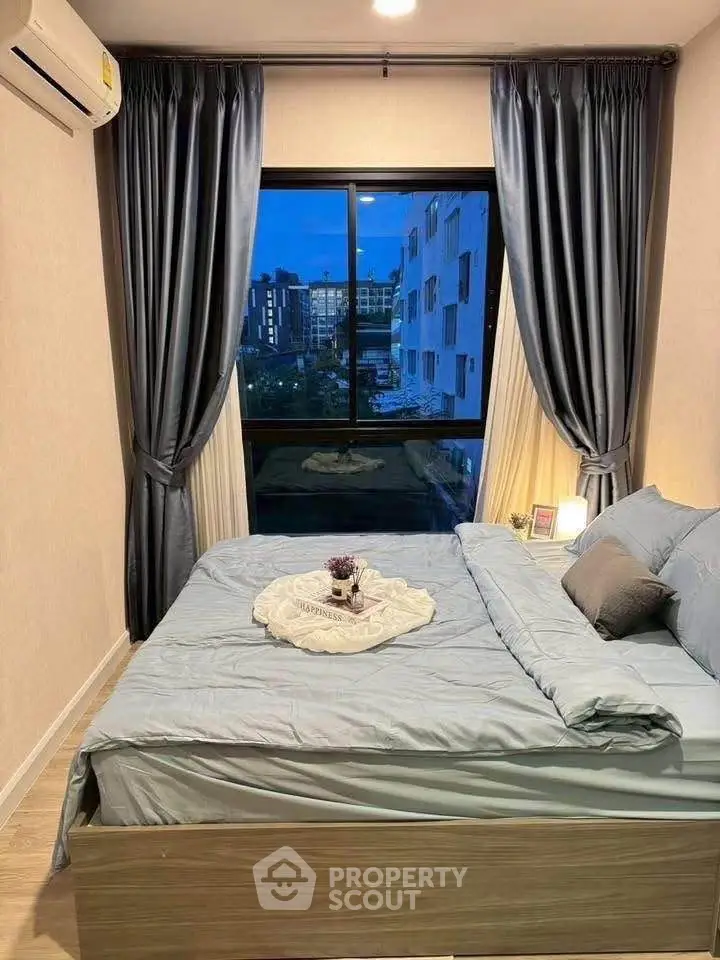 Modern bedroom with city view, stylish curtains, and cozy bedding in urban apartment.