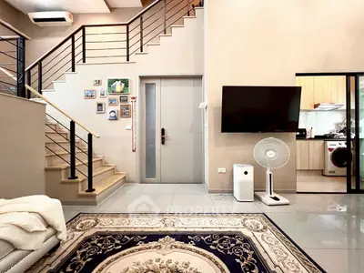 Modern living room with staircase, wall art, and open kitchen view
