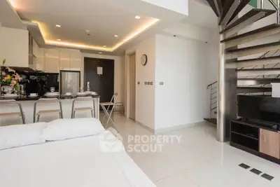 Modern open-plan living room with sleek kitchen and spiral staircase in stylish apartment.