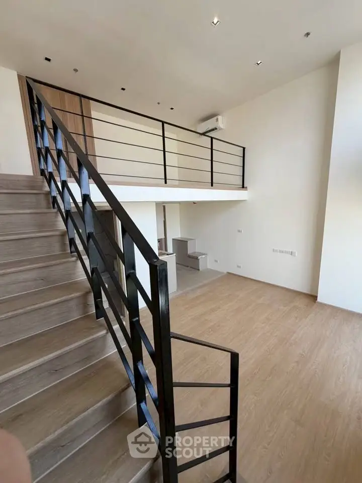 Modern duplex apartment with sleek staircase and open layout, featuring high ceilings and wooden flooring.