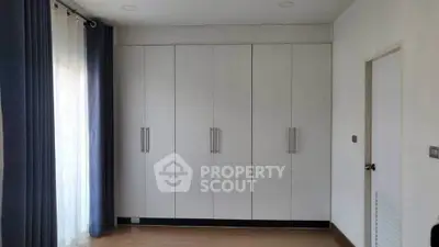 Spacious bedroom with large built-in wardrobe and elegant curtains.