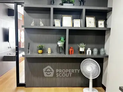 Modern living room with stylish shelving and decorative plants, featuring a sleek fan and wooden flooring.
