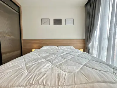 Modern bedroom with cozy bed and elegant decor, featuring large window with sheer curtains.