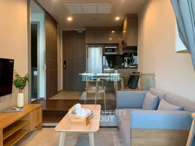 Modern living room with open kitchen, stylish furniture, and cozy ambiance in a contemporary apartment.