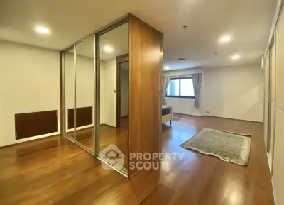 Spacious modern living room with wooden flooring and large mirrored closet