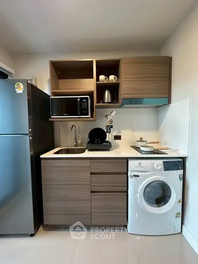 Modern compact kitchen with sleek cabinetry, stainless steel appliances, and washing machine.