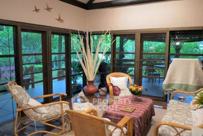 Charming living room with rattan furniture and lush garden view.