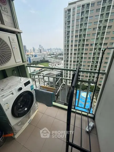 High-rise balcony with city view, featuring washing machine and air conditioning unit.
