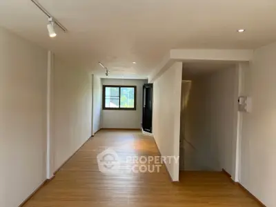 Spacious minimalist interior with wooden flooring and ample natural light.