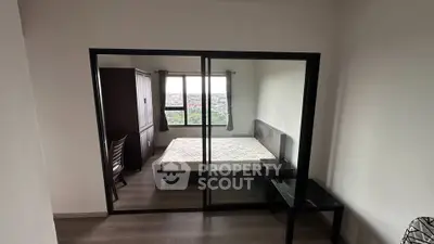 Modern bedroom with large window and mirrored sliding doors, offering a spacious and bright atmosphere.