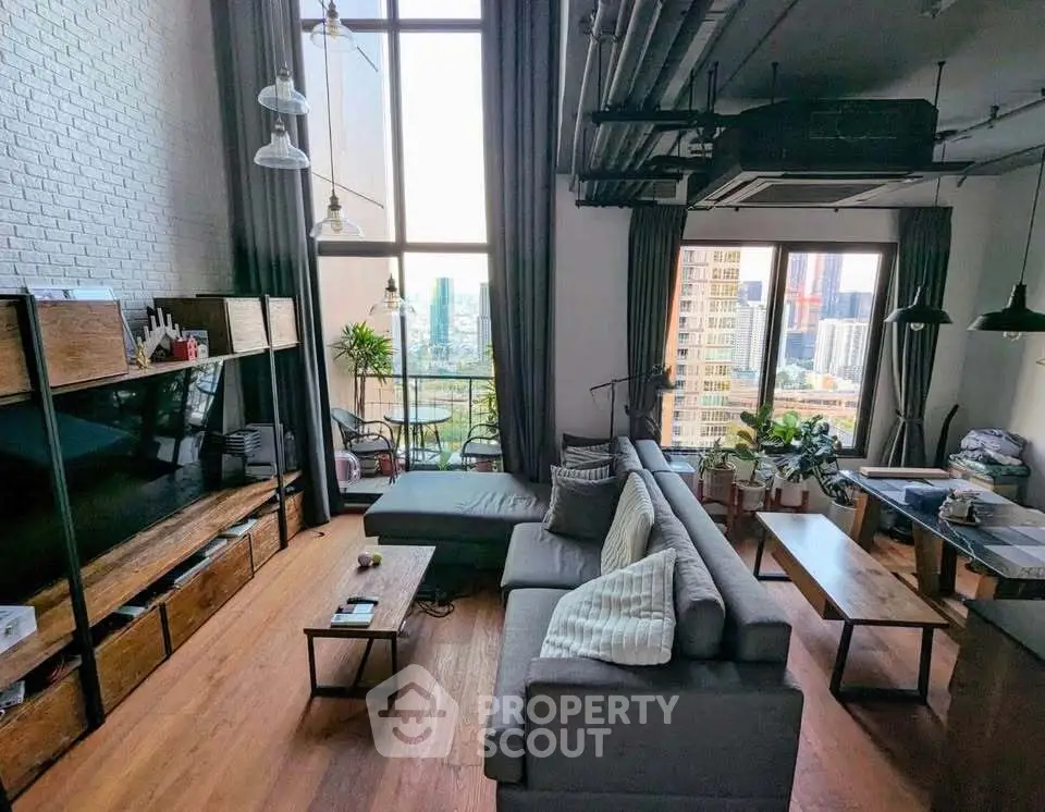 Stunning modern living room with high ceilings and city view, featuring stylish furniture and large windows.