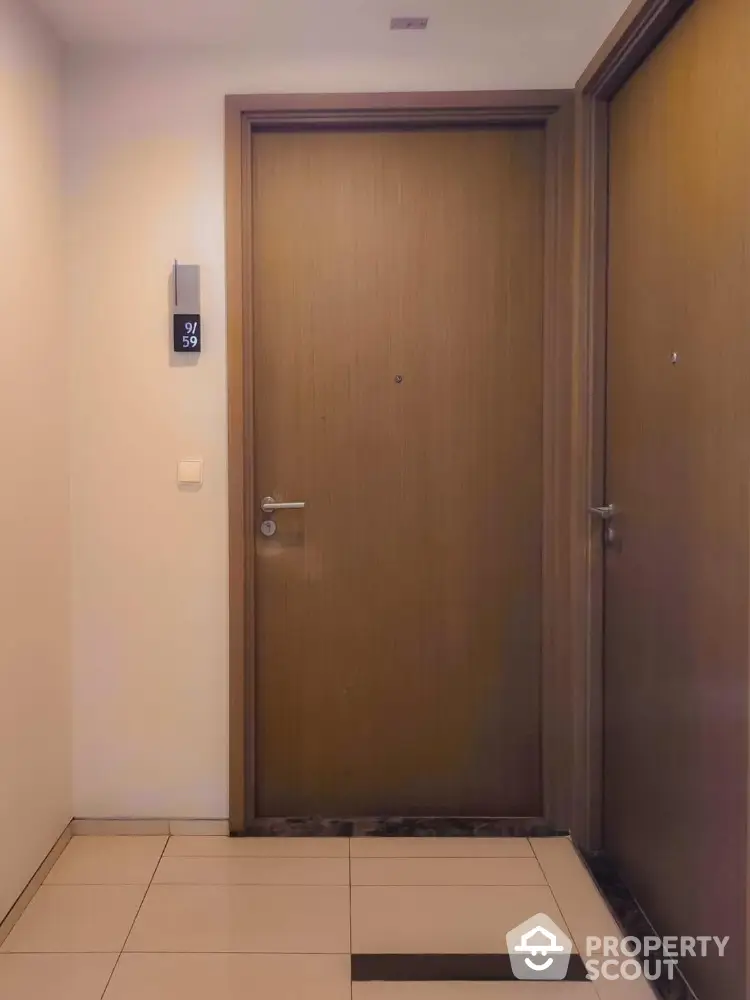 Modern apartment entrance with sleek wooden door and tiled flooring