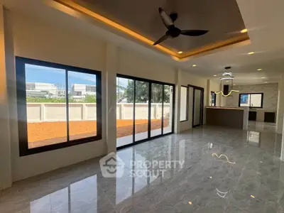 Spacious modern living room with large windows and sleek kitchen, perfect for entertaining.