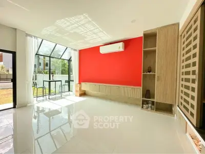 Spacious modern living room with vibrant red accent wall and large windows for natural light.