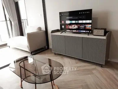 Modern living room with sleek TV stand, glass coffee table, and large window for natural light.