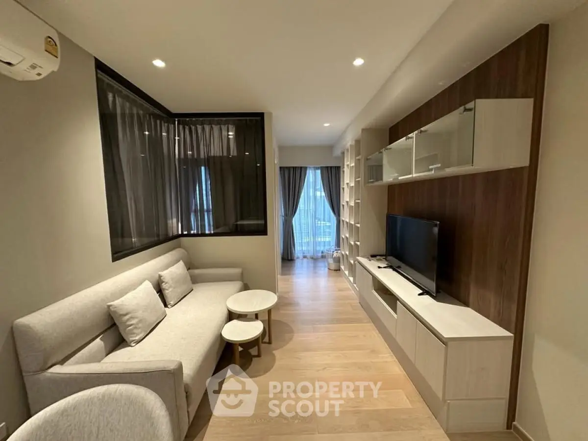 Modern living room with sleek furniture and large window offering city view