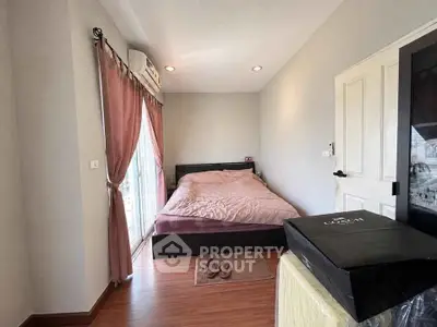 Cozy bedroom with wooden flooring and large window, featuring a comfortable bed and stylish decor.