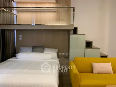 Modern studio apartment with loft bed and vibrant yellow sofa