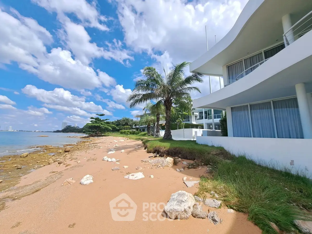 Stunning beachfront property with modern architecture and lush palm trees, offering breathtaking ocean views.