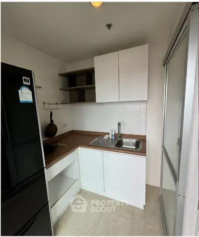 Modern compact kitchen with sleek white cabinets and stainless steel sink in a cozy apartment.