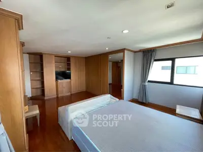 Spacious bedroom with wooden flooring and built-in wardrobe, featuring large windows for natural light.