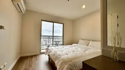 Spacious bedroom with balcony and modern decor in a high-rise apartment.